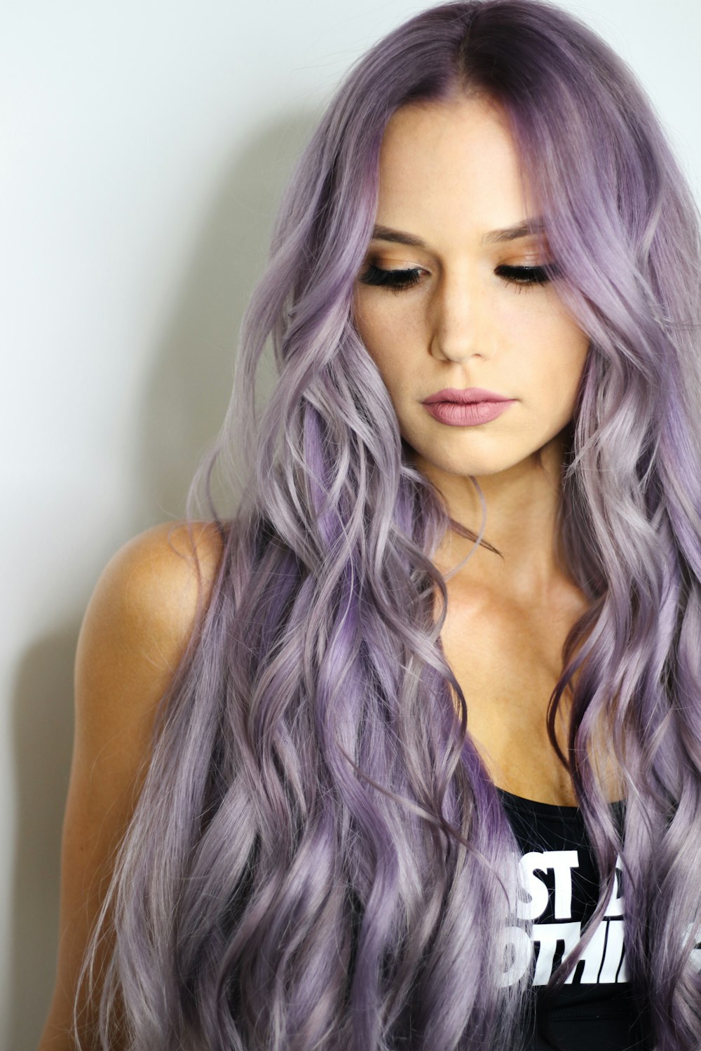 purple haired woman in black top leaning on wall