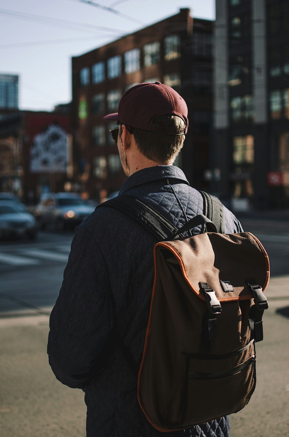 homme portant une veste et une casquette noires debout près de la route regardant vers l’avant