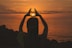 silhouette of woman doing heart sign during sunset