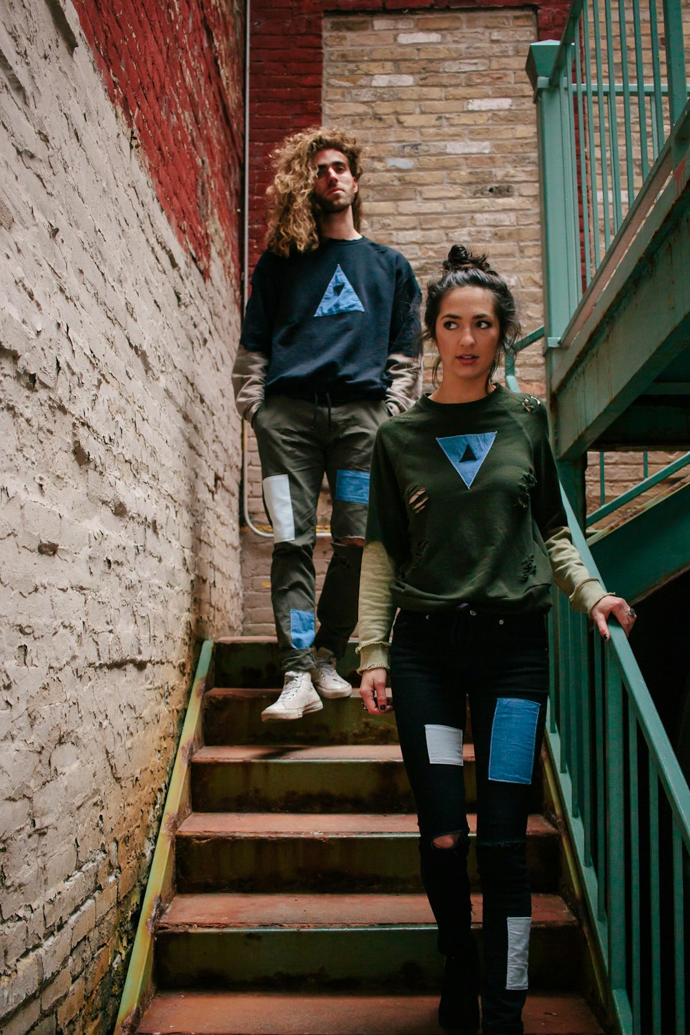 A young woman and a young man walking down the stairs in an old brick stairwell