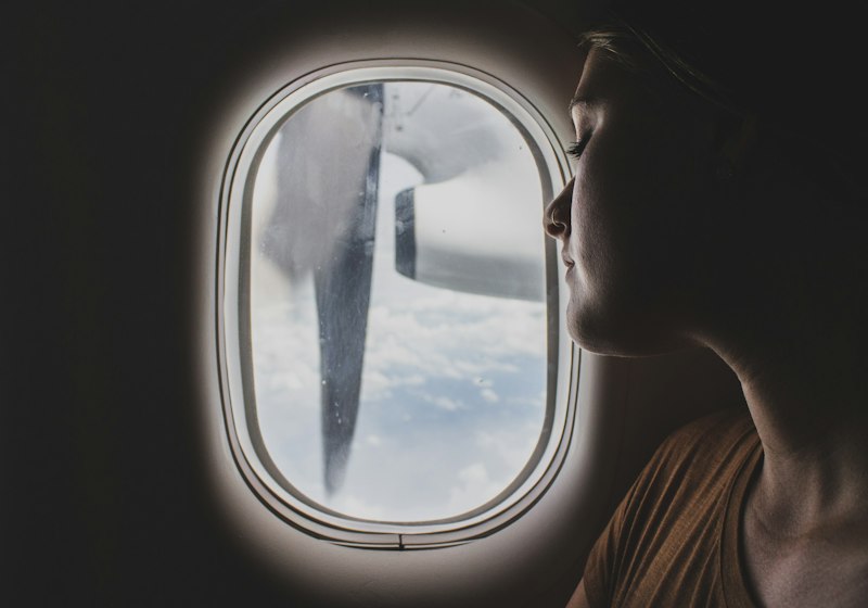 Person sitting quietly near an airplane window during flight