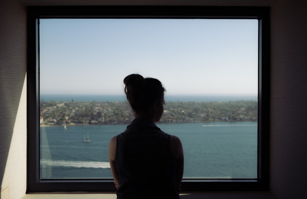 woman wearing off-shoulder shirt standing beside window