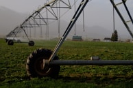 Engineers collaborating over blueprints with irrigation machinery in background.