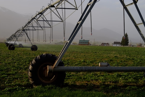 Sprayers and irrigation equipment displayed outside a local agricultural supply shop against a mountainous backdrop.