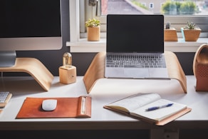 A sleek modern workspace with a laptop, green plants, and a notebook, reflecting a minimalist and fresh business environment