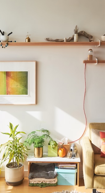 A cozy living room corner featuring a wooden clock on the wall, an abstract canvas print above a fringed cotton rug, and a brass candle holder glowing softly on a side table.