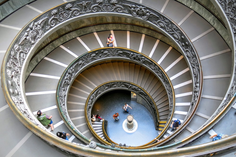 Looking down a massive spiral staircase while people climb up in the Vatican Museums