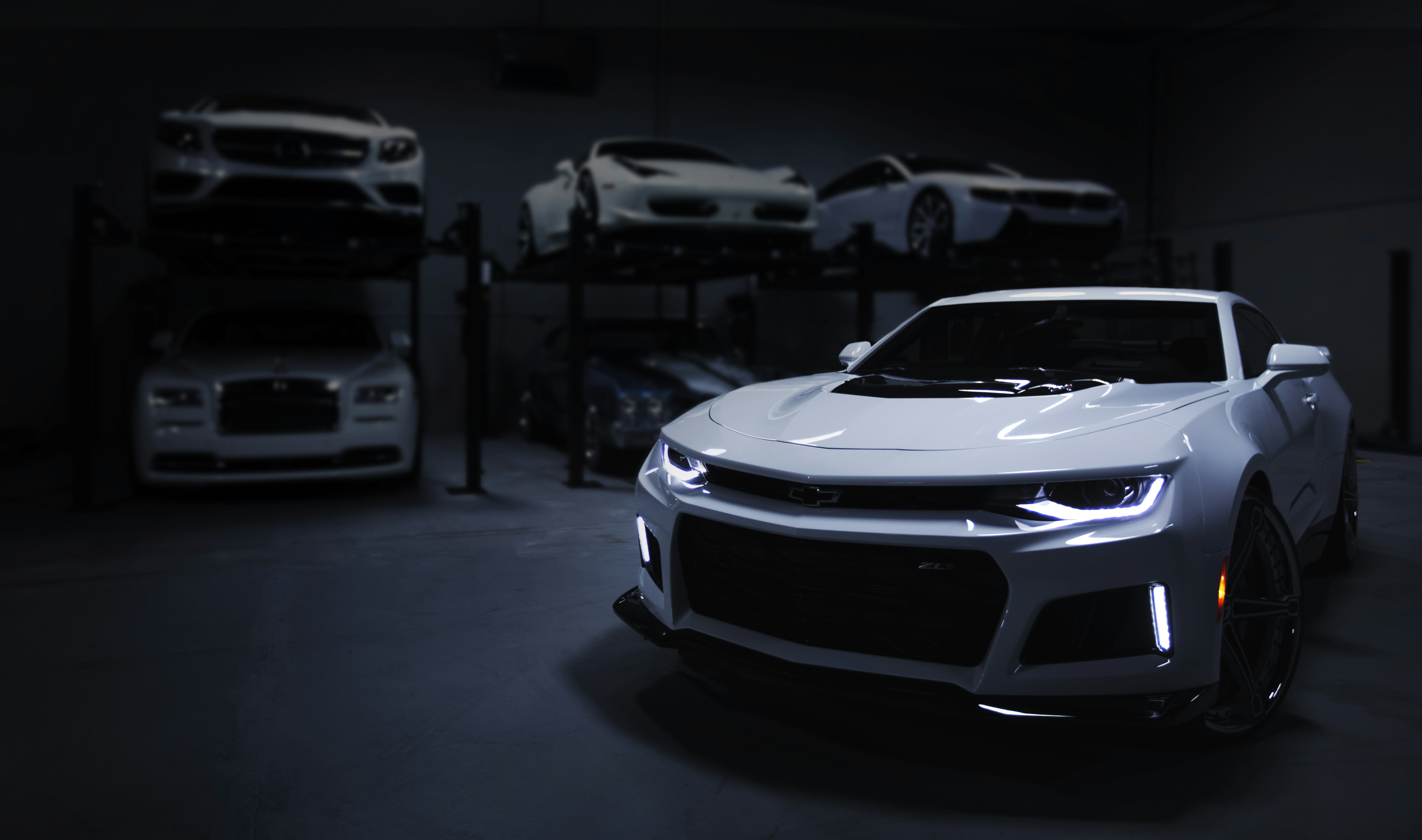 great photo recipe,how to photograph i shot this while doing a job for a luxury automotive storage facility in baltimore, md. i wanted to create an ominous sense of intrigue, giving the feeling of a space that was both expansive and enclosed. i enjoy the journey my eyes take from the focal point of the headlamps to the contours of the camero’s body, and then to the backdrop of stacked automobiles.; white car