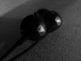 Close-up of sleek black matte Holobuds with soft blue and purple holographic light reflections floating against a dark background