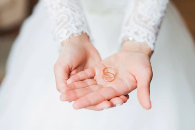 A close-up of wedding rings resting on an elegant lace cloth beside a handwritten vow.