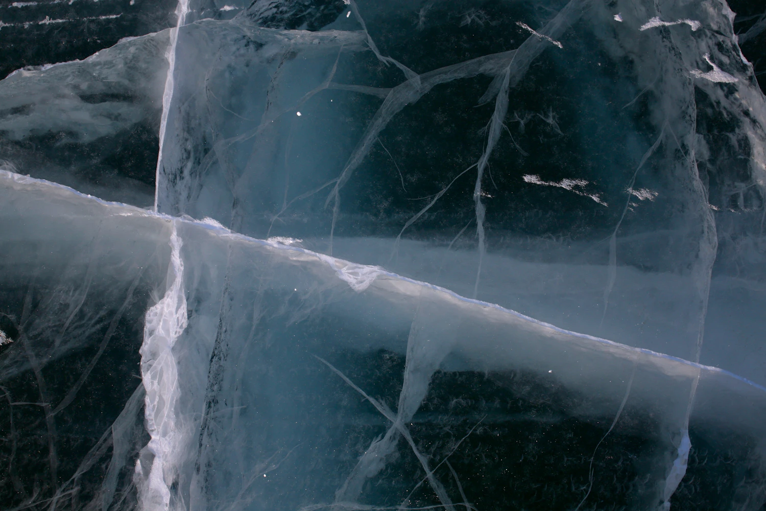 Frozen surface lit from below, cracks branching away from a central point