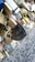 A collection of various padlocks attached to a metal fence, including traditional brass locks, a large vintage lock, and a few colorful locks. Some locks have inscriptions, and the surface beneath them appears to be weathered concrete.