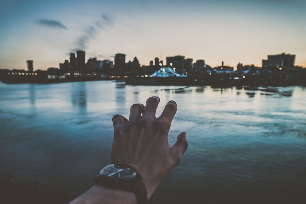 mão esquerda da pessoa alcançando paisagens da cidade fotografia