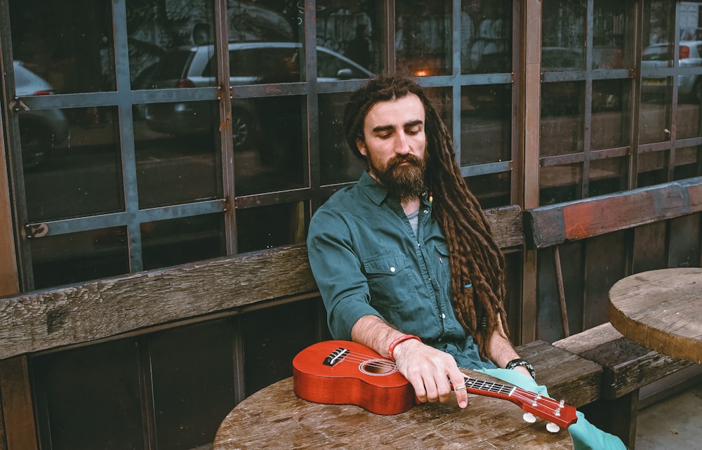 man in blue sport shirt holding ukulele