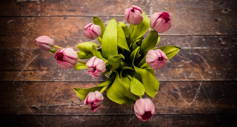 pink petaled flower centerpiece on brown wooden surface in high angle shot