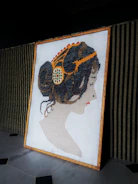 Artistic string art portrait of a woman with flowing hair made from multicolored threads.