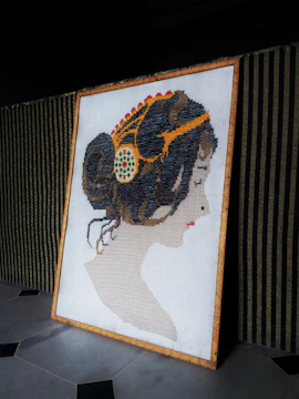 Artistic string art portrait of a woman with flowing hair made from multicolored threads.