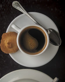 A steaming cup of dark espresso placed on a saucer beside coffee grounds