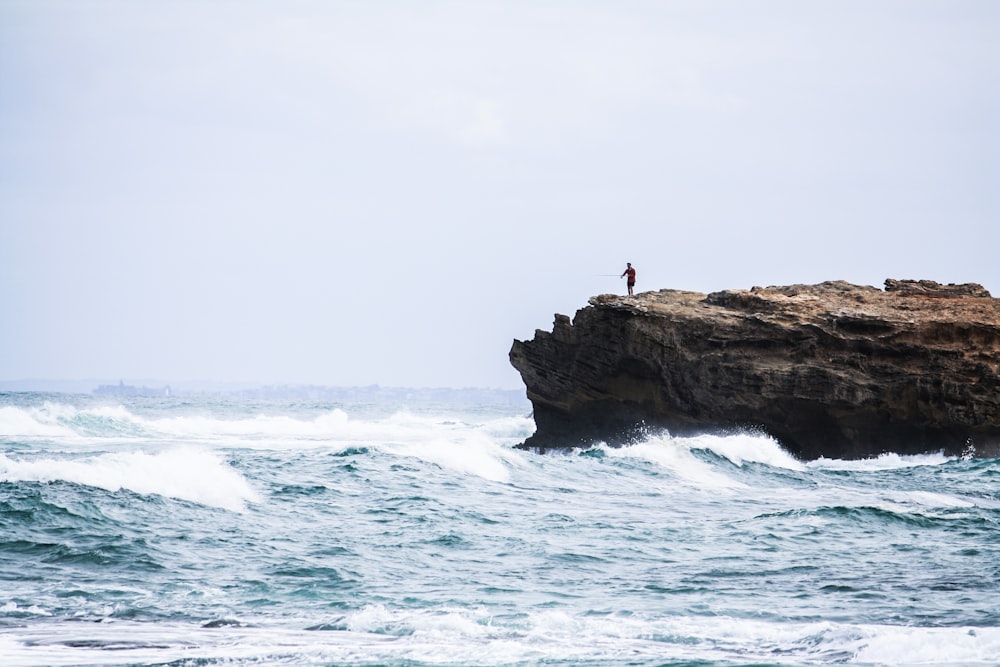 homme debout sur le rocher regardant la mer