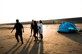 A group of Pacific practitioners gathered on a beach, sharing stories under a vibrant sunset.