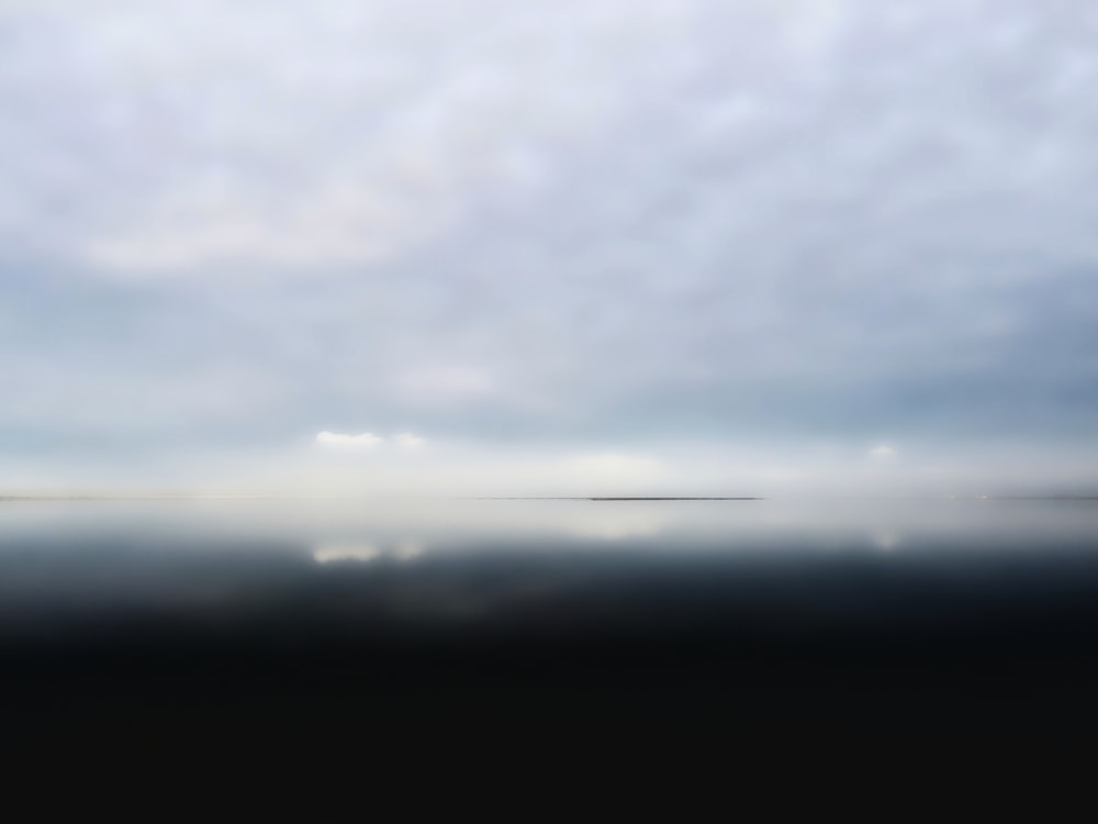 a blurry photo of a body of water under a cloudy sky