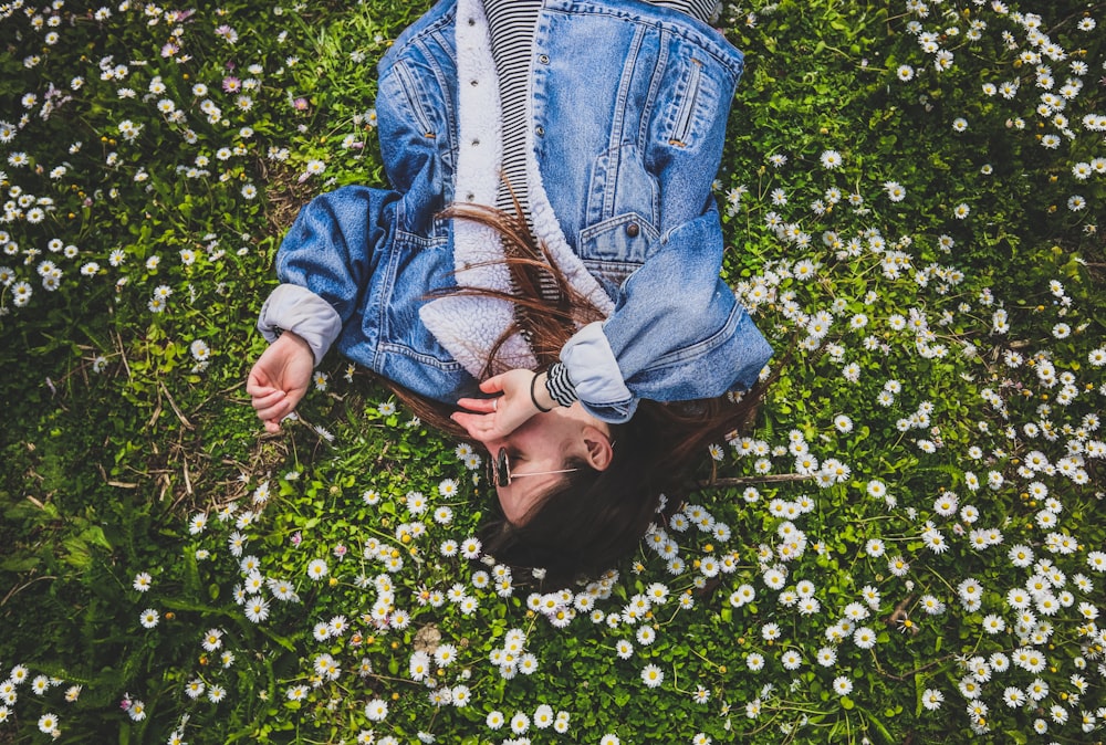 woman lying on bed of white petaled flower