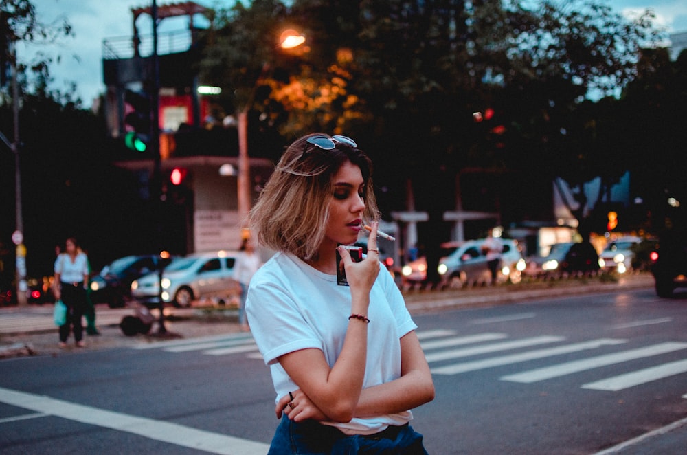 woman smoking single cigarette near vehicles and people