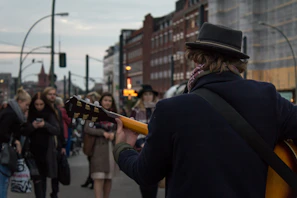 A candid shot of a street musician playing guitar on a busy sidewalk.