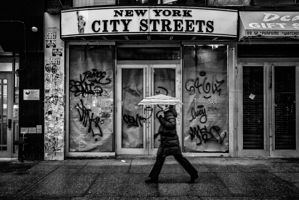 person holding umbrella and walking on street