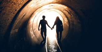 silhouette of man and woman inside tunnel