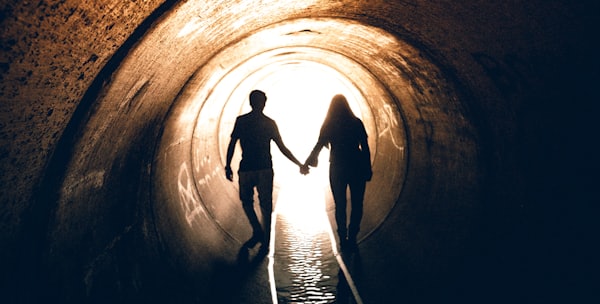 silhouette of man and woman inside tunnel