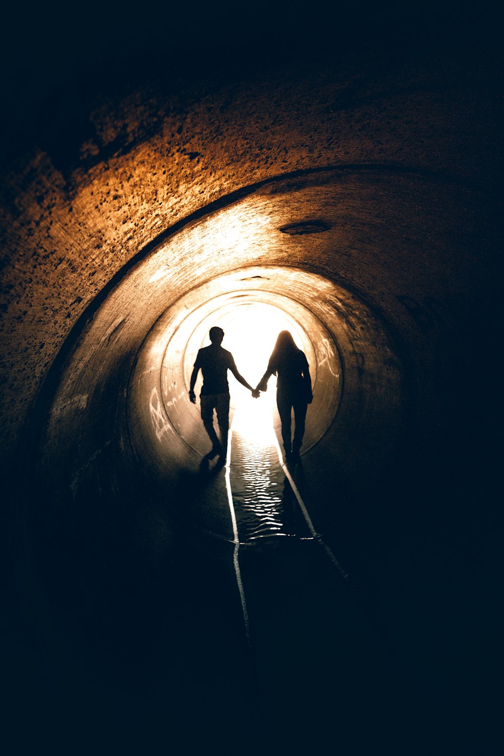 silhouette of man and woman inside tunnel