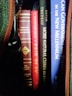 A collection of books is visible with titles such as 'American Historical Documents', 'Fair Play', 'More Natural Cures Revealed', and parts of others. The books are neatly lined up with various colored spines, including red, black, and blue.