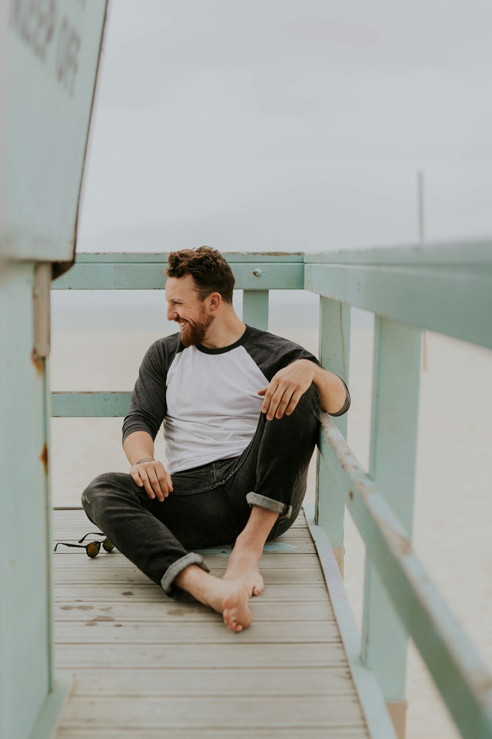 homme souriant tout en étant assis sur le sol pendant la journée