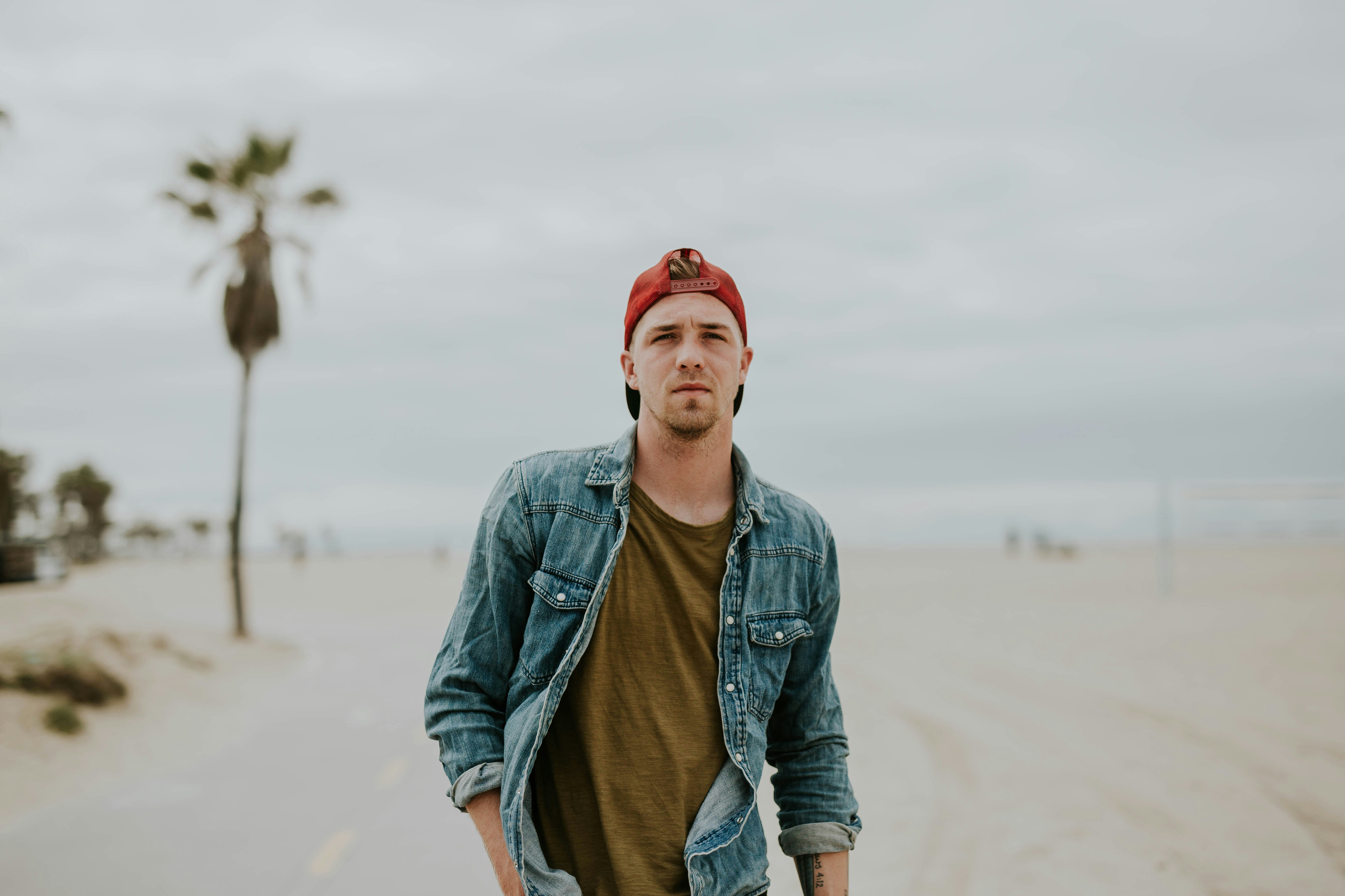 man standing on road between sand