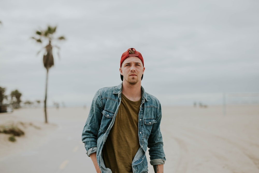 man standing on road between sand