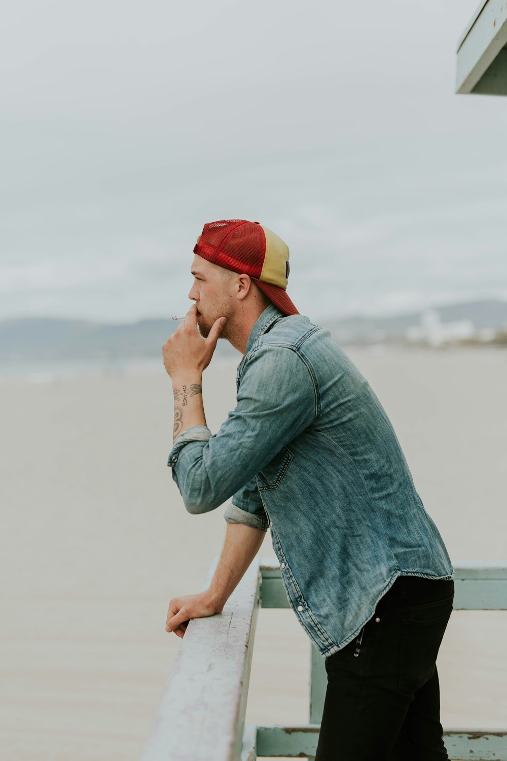 man standing beside handrail overlooking body of water