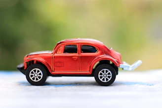 A bright red toy car with shiny wheels, captured in motion on a black background.