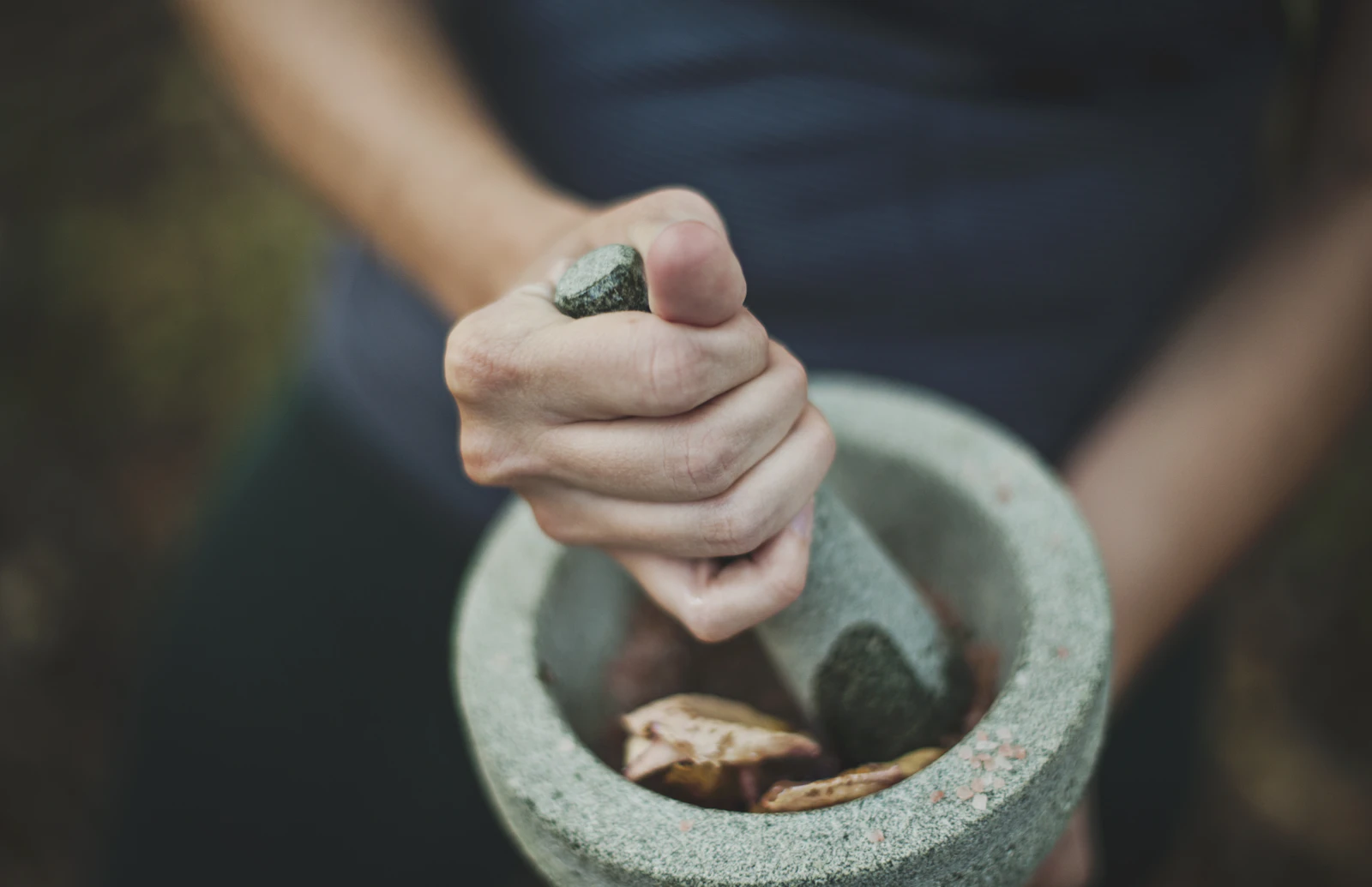 Herbal botanicals being ground with a mortar and pestle