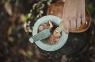 high angle photo of person pouring liquid from bottle inside mortar and pestle frankincense teams background