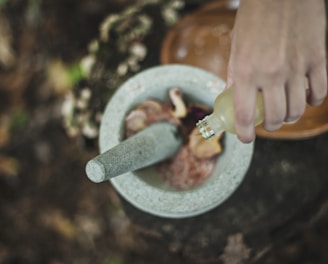 high angle photo of person pouring liquid from bottle inside mortar and pestle