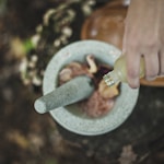 high angle photo of person pouring liquid from bottle inside mortar and pestle