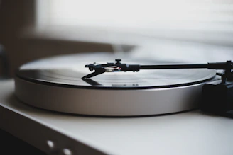 Close-up of a sleek black turntable spinning a vinyl record in a softly lit room.