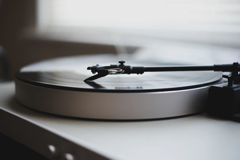 Close-up of a vintage vinyl record spinning on a rustic wooden turntable bathed in soft natural light
