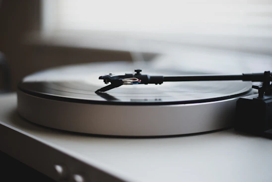 Close-up of a sleek black turntable spinning a vinyl record in a softly lit room.