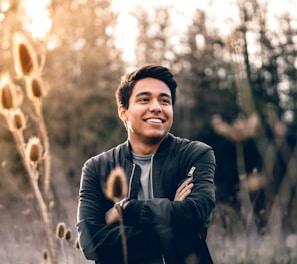 smiling man standing near green trees