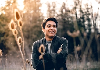 smiling man standing near green trees