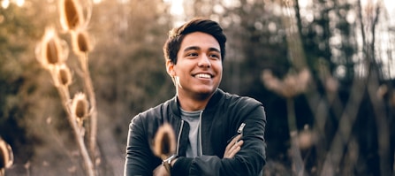 smiling man standing near green trees