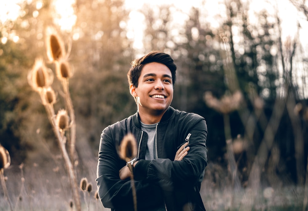 Hombre sonriente de pie cerca de los árboles verdes