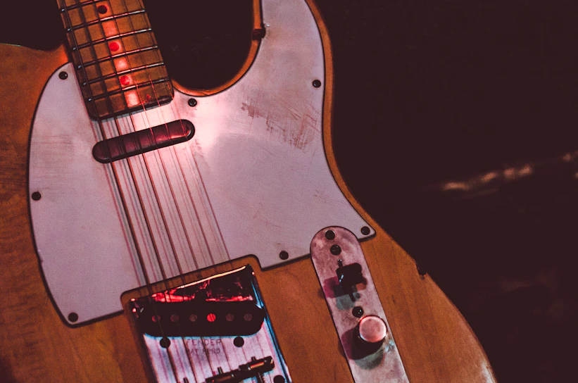 Close-up of a vintage guitar showing worn frets and a small scratch near the bridge.